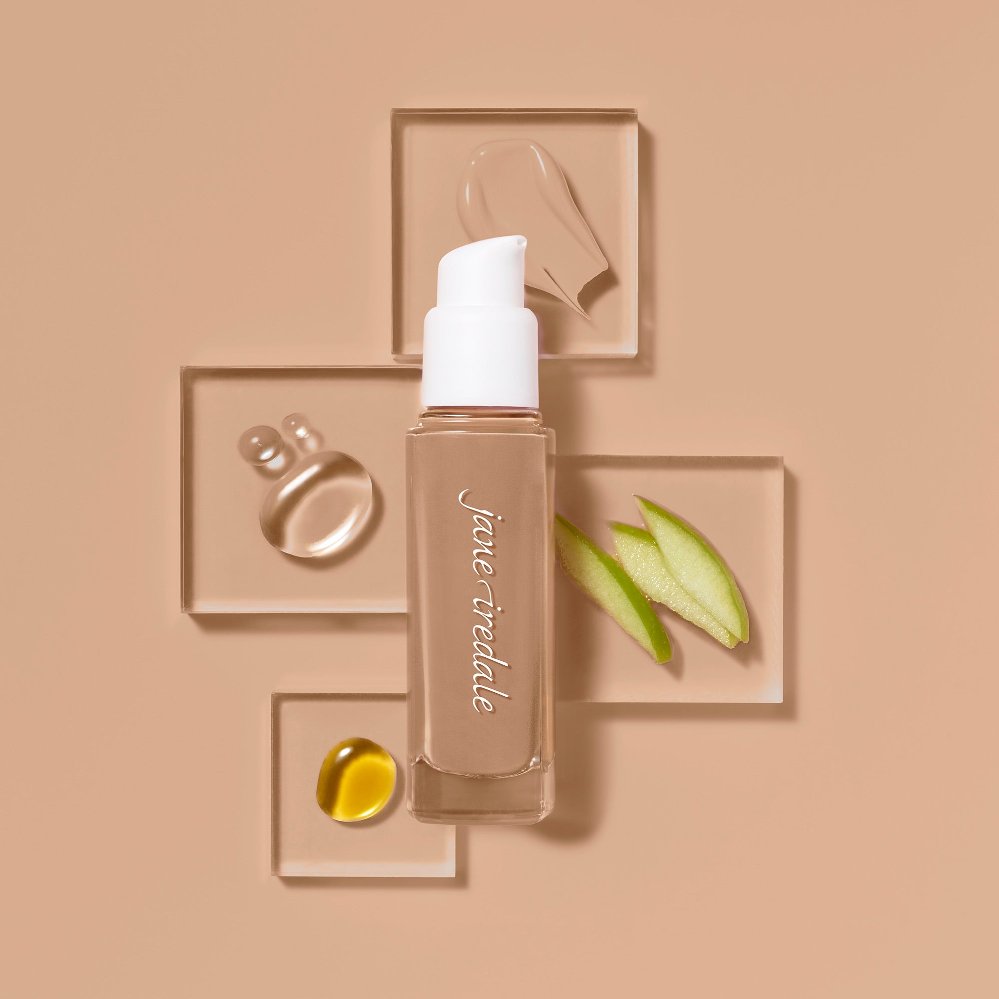 Die jane iredale Flüssigfoundation Skintuition in einer Glasflasche mit Pumpspender, umgeben von Abbildungen enthaltener Inhaltsstoffe