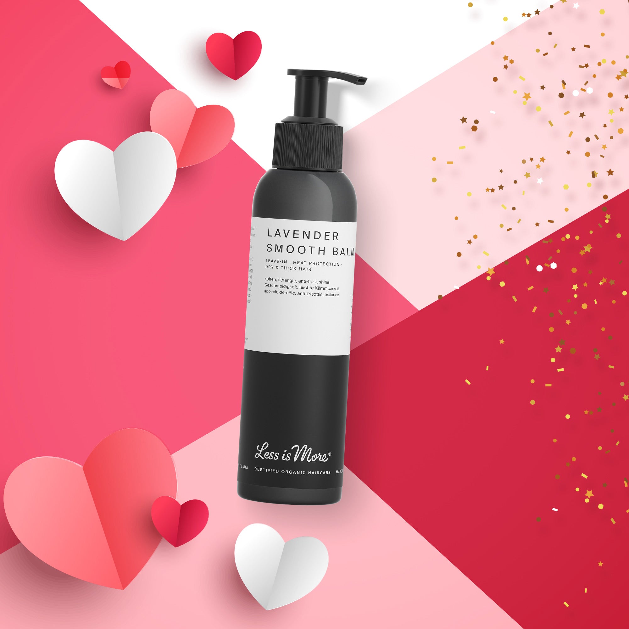 Schwarze Pumpflasche mit weißem Etikett der Marke „Less is More“, Produktname „Lavender Smooth Balm“. Die Flasche liegt schräg auf einem geometrisch geteilten rosa-roten Hintergrund. Um die Flasche sind Papierherzen in Rot, Rosa und Weiß sowie goldene Konfettipunkte angeordnet.