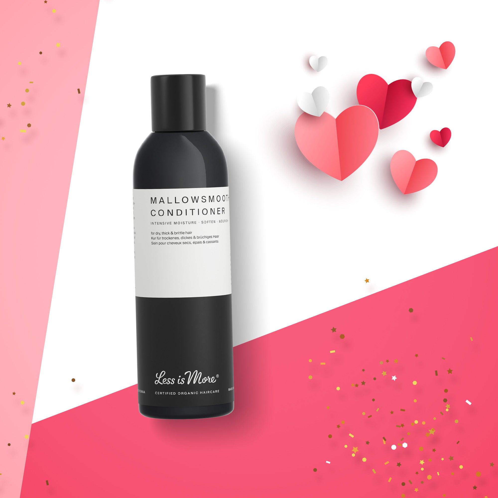 Schwarze Flasche mit weißem Etikett der Marke „Less is More“, Produktname „Mallowsmooth Conditioner“. Die Flasche liegt schräg auf einem weißen und kräftig rosa Hintergrund. Daneben befinden sich mehrere Papierherzen in verschiedenen Rot- und Rosatönen sowie goldene Konfettipunkte.