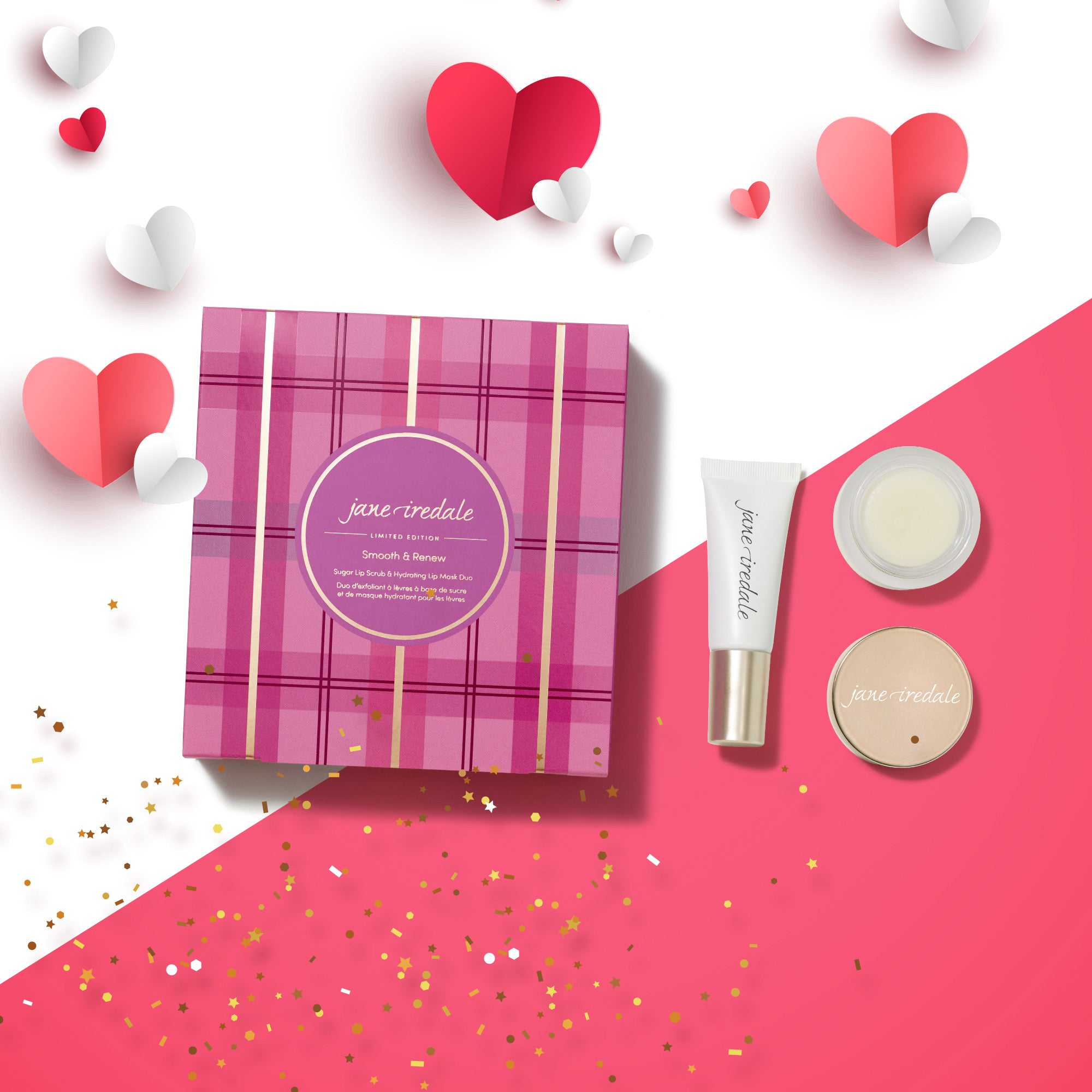 Geschenkbox im pink karierten Design mit rundem Etikett „Jane Iredale – Smooth & Renew“. Rechts davon stehen drei Produkte: eine Tube, ein kleiner Tiegel und ein runder kompakter Behälter. Die Produkte liegen auf einem rosa-weißen Hintergrund, dekoriert mit Papierherzen in Rot, Rosa und Weiß sowie goldenem Konfetti.
