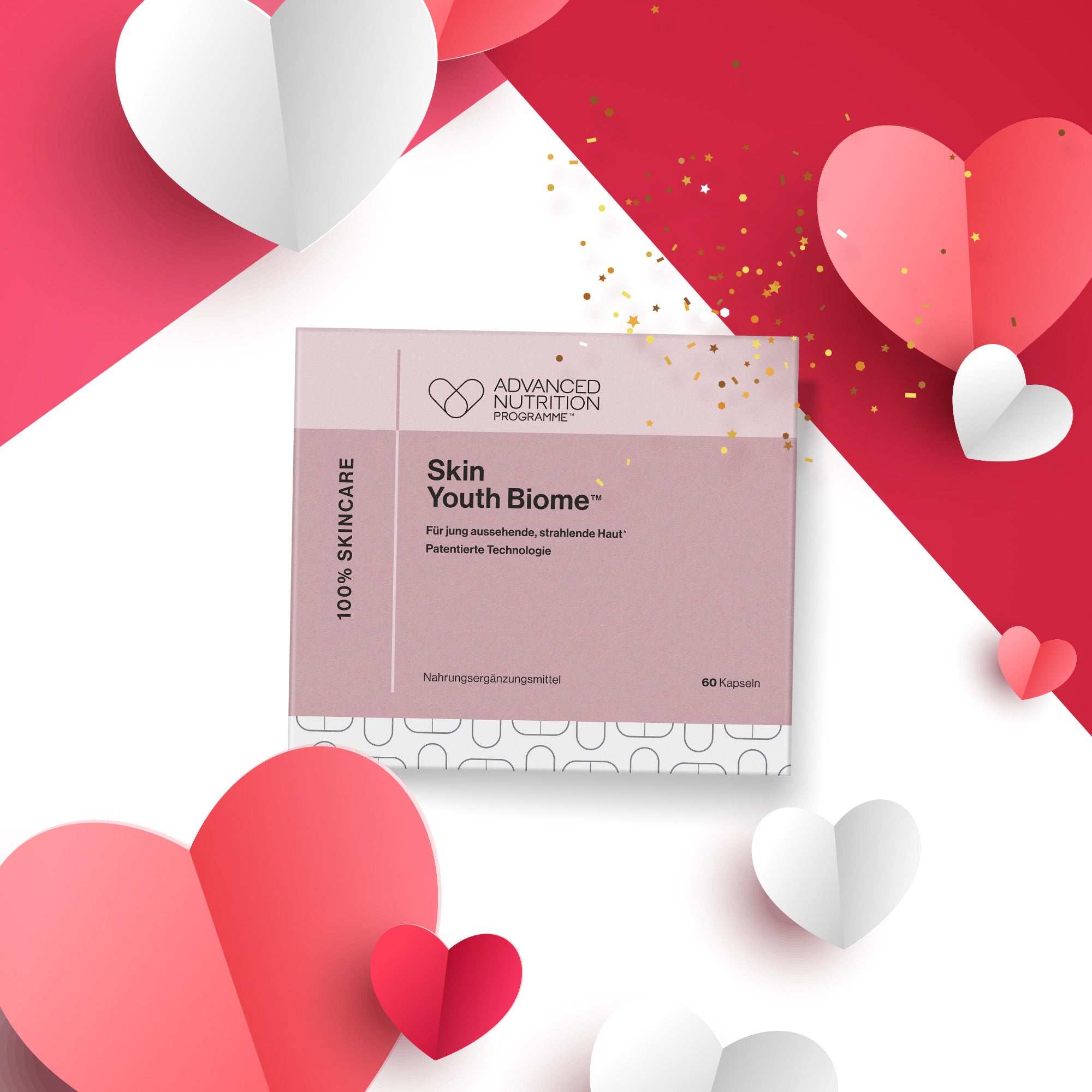Rosa Produktverpackung „Skin Youth Biome“ mit textbasiertem Etikett. Die Verpackung liegt auf einem rosa-weißen Hintergrund, dekoriert mit Papierherzen in verschiedenen Rot- und Rosatönen sowie goldenen Konfettipartikeln.