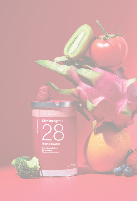 Rote Produktdose von ADVNACED NUTRITION PROGRAMME mit der Aufschrift ‚Skin Integrate 28 Biome powder‘ neben frischem Obst und Gemüse wie Kiwi, Tomate, Drachenfrucht, Orange, Himbeere, Blaubeeren, Erdbeere und Brokkoli vor rotem Hintergrund.