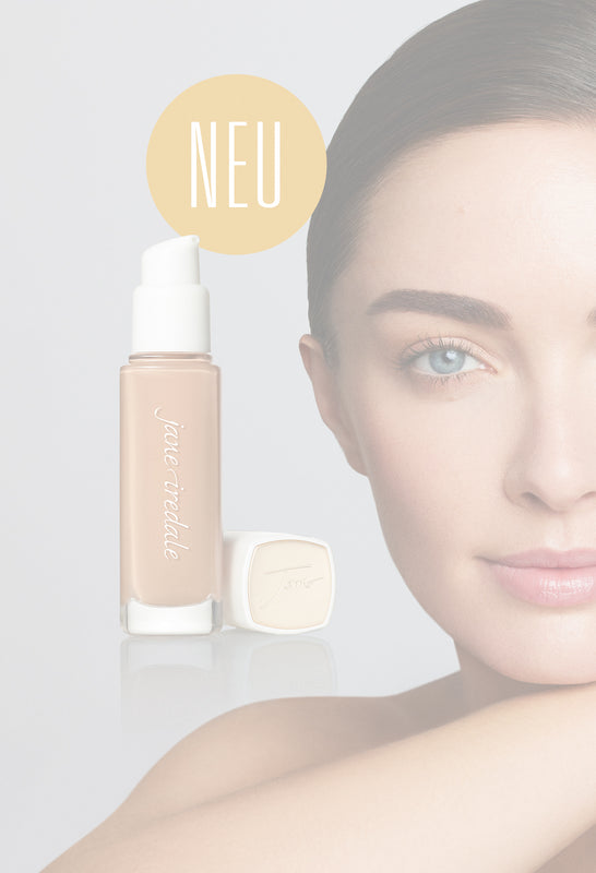 Ein Model schaut freundlich aber neutral in die Kamera, daneben eine Glasflasche der jane iredale Flüssigfoundation Skintuition und das Wort NEU in einem Kreis