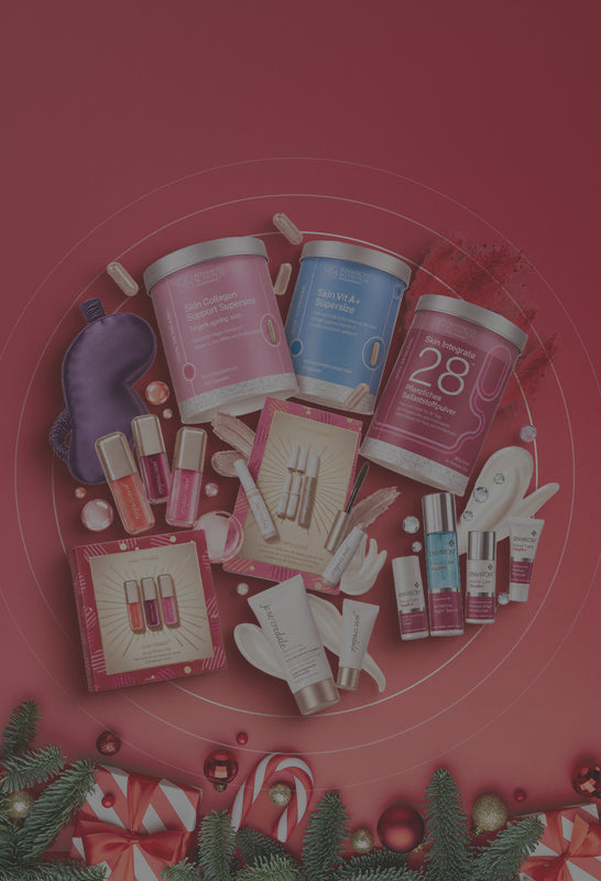 Weihnachtliches Werbemotiv mit schwebenden Hautpflege-, Make-up- und Nahrungsergänzungsprodukten von Environ, jane iredale und Advanced Nutrition Programme vor rotem Hintergrund, eingerahmt von Tannenzweigen, Christbaumkugeln und Geschenken.